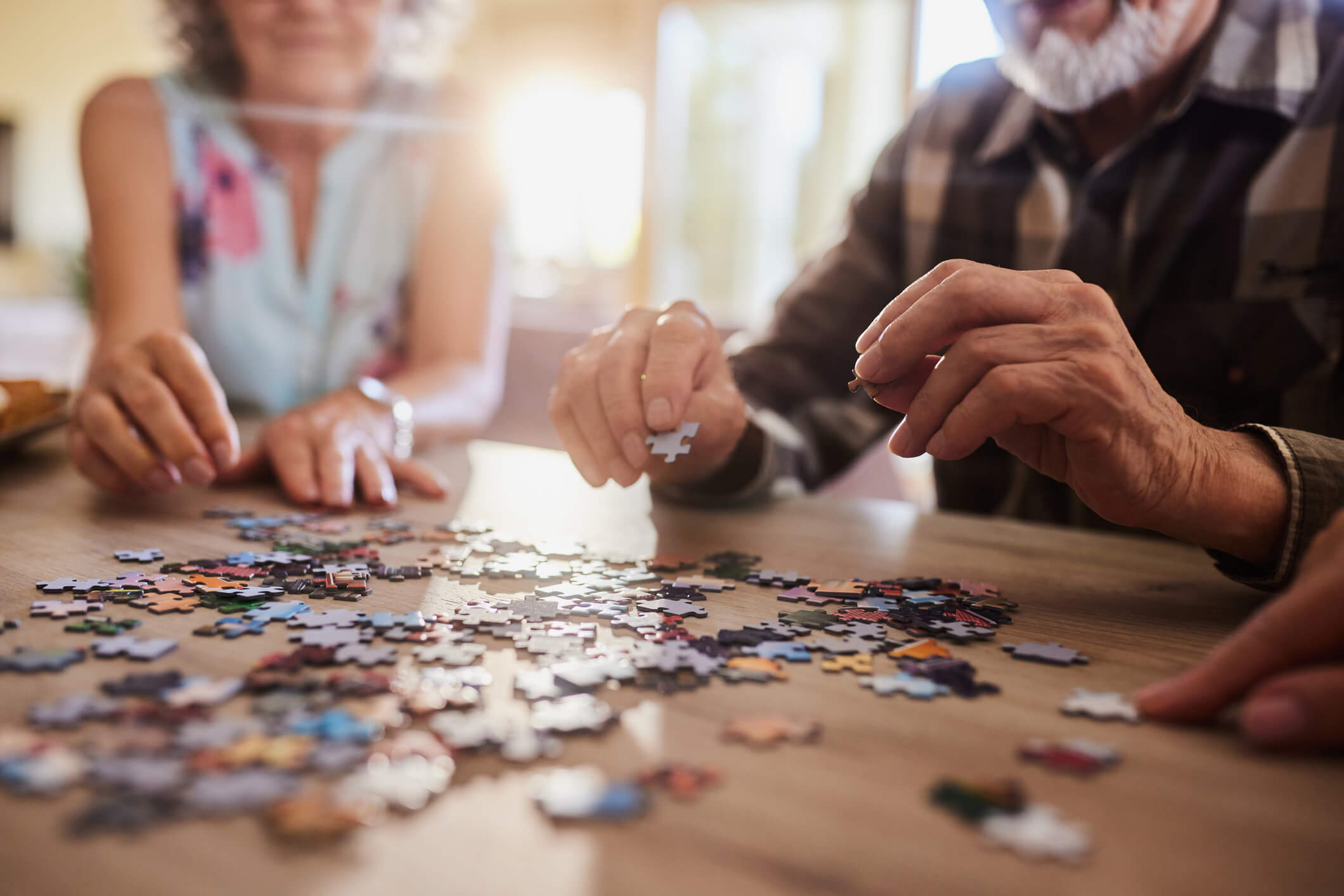 Close up of mature couple playing with jigsaw puzzles at home.